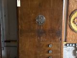 a wooden cabinet in a room with a clock on the wall