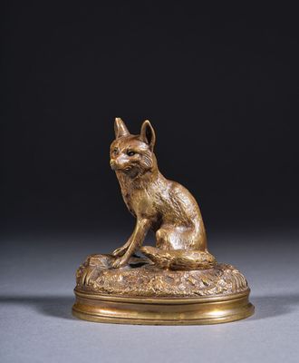 une statue en bronze représentant un chat assis sur un rocher