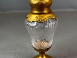gold and clear glass vase with a gold lid on a white surface