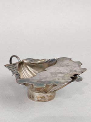 une assiette en argent ornée d'une fleur sur un fond blanc