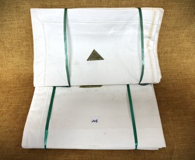 deux draps blancs bordés de vert sont empilés l'un sur l'autre