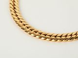 a close up of a gold necklace on a white surface
