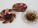trois petits plats posés sur une table blanche, avec une fleur rouge au centre