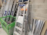 Plusieurs échelles sont empilées contre un mur dans un entrepôt.