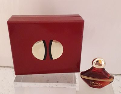 une boîte rouge avec un flacon de parfum à côté
