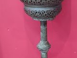a metal lamp that is on a stand in front of a pink wall