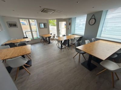 many tables and chairs in a room with a clock on the wall