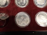 six silver coins in a red case with a ring on top of them