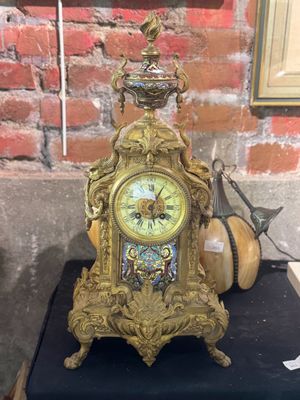 une horloge dorée posée sur une table noire devant un mur de briques