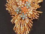 a gold brooch with blue and orange stones on it