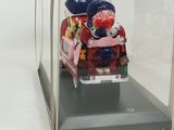 a figurine of a man sitting on a couch in a glass case