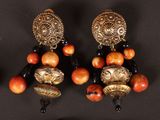 three pairs of gold and black earrings on a black surface