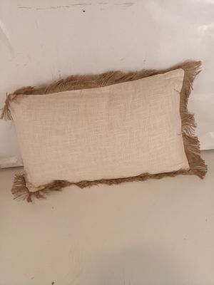 un oreiller aux bords effilochés posé sur un lit dans une chambre à coucher