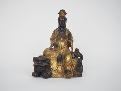 une statue en or représentant un homme assis sur un rocher avec un chien