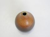 a brown vase with a hole in it on a white surface