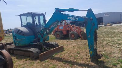 a blue excavator that is sitting in the grass