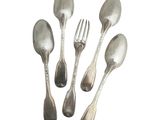 quatre cuillères et une fourchette en argent sur une surface blanche