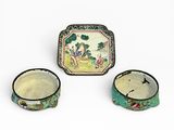 Trois pièces de poterie chinoise sont posées sur une surface blanche