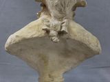 a statue of a dog sitting on top of a stone bust