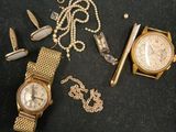 a gold watch, a gold chain, and a gold watch on a black surface