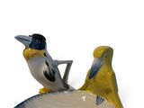 two figurines of birds sitting on top of a shell