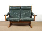 a pair of green leather couches sitting on a carpeted floor