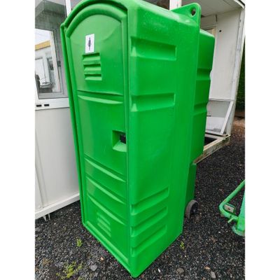 des toilettes portables vertes posées sur un sol en gravier