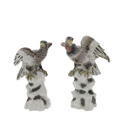 two figurines of birds sitting on top of a tree stump