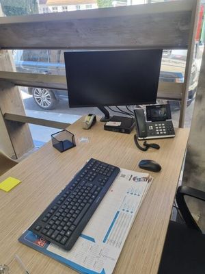 un bureau sur lequel se trouvent un clavier, un téléphone et un écran