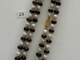 a white and black beaded necklace with a gold clasp