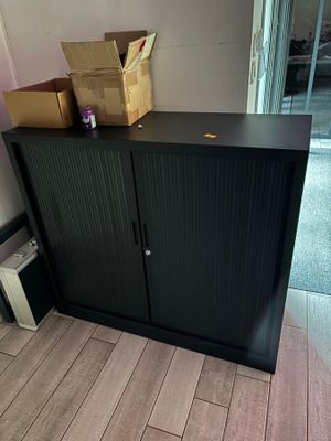 une armoire noire surmontée de boîtes, dans une pièce