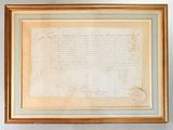 an old document is hanging on a wall next to a vase