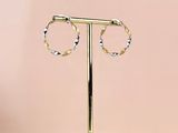 une paire de boucles d'oreilles créoles en or posée sur un socle en marbre