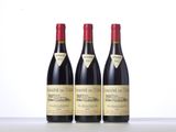 three bottles of red wine are lined up on a table
