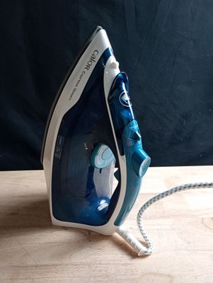 un fer à repasser bleu et blanc posé sur une table en bois