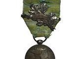 une vieille médaille en argent, suspendue à un ruban vert