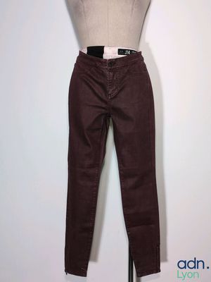 le mannequin tient un pantalon marron sur son support