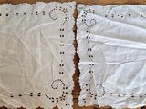deux morceaux de lin blanc posés sur une table en bois, avec une paire de ciseaux