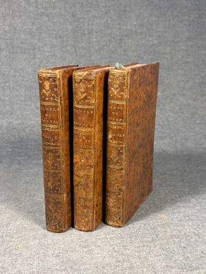three old books sitting on top of each other on a gray surface