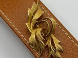 leather belt with a gold buckle and a flower on it