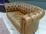 a brown leather couch sitting on a tiled floor in a room
