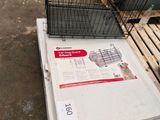 un chien dans une cage posée sur une palette, à côté d'autres cages