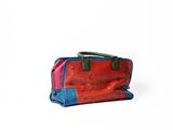 a red and blue handbag sitting on a white surface