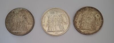 trois pièces d'argent posées les unes à côté des autres sur une surface blanche
