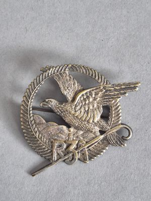 une image représentant une broche en argent sur laquelle figurent un oiseau et un autre oiseau perché sur une branche
