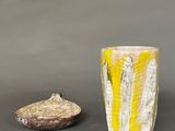 yellow and white vase and rock on a gray surface