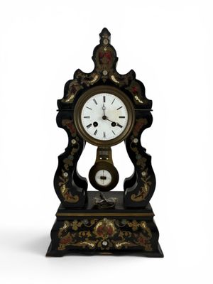 une horloge noire et or posée sur une surface blanche