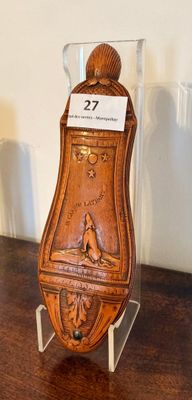 une horloge en bois posée sur un socle, elle-même posé sur une table