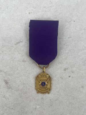 a close up of a purple ribbon with a gold medal on it