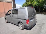 a grey van parked in a parking lot with trees in the background